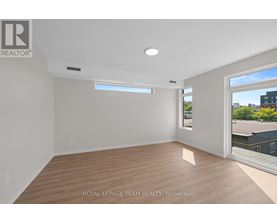 A spacious room with wooden flooring and a large window.