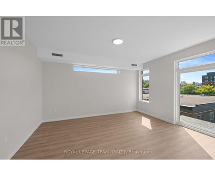A spacious room with wooden flooring and a large window.