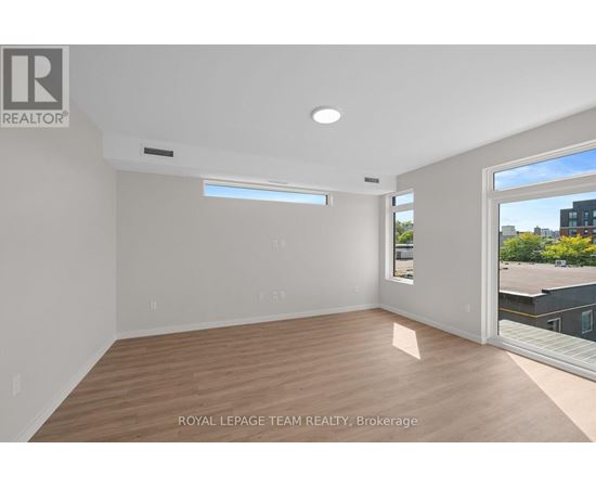 A spacious room with wooden flooring and a large window.