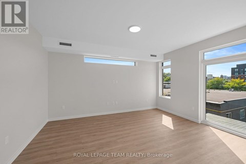 A spacious room with wooden flooring and a large window.