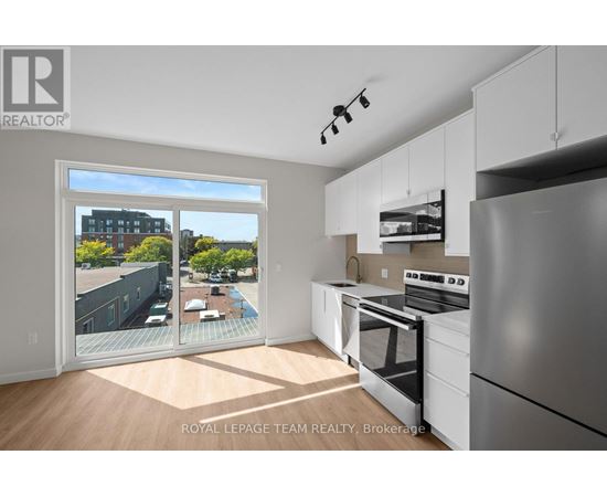 A kitchen with white appliances and cabinets with a view of a pool and buildings outside.