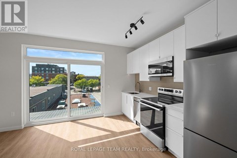 A kitchen with white appliances and cabinets with a view of a pool and buildings outside.