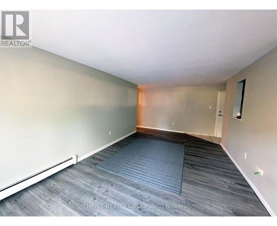 A room with a grey carpet and wooden flooring.
