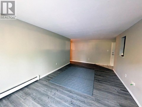 A room with a grey carpet and wooden flooring.