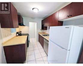 A kitchen with a white fridge and brown cabinets.