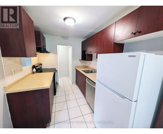 A kitchen with a white fridge and brown cabinets.