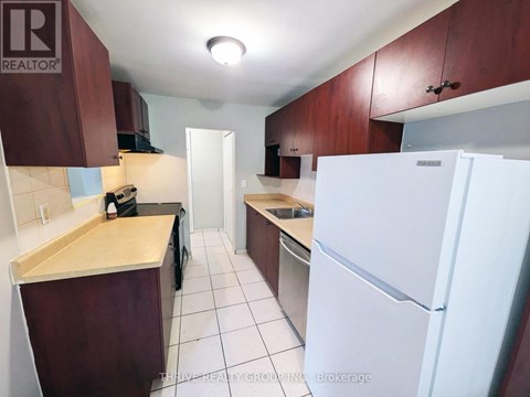A kitchen with a white fridge and brown cabinets.