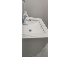 A white sink with a silver faucet and a blue knob.