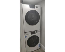 A white washing machine with a black door is stacked on top of another white washing machine with a black door.