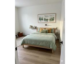 A bedroom with a bed, nightstands, and a painting on the wall.
