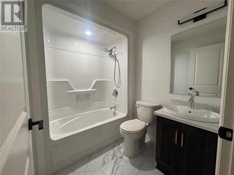 A white bathroom with a toilet, sink, and shower.