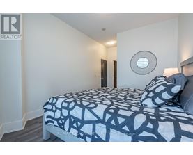 A bedroom with a bed covered in a black and white patterned comforter.