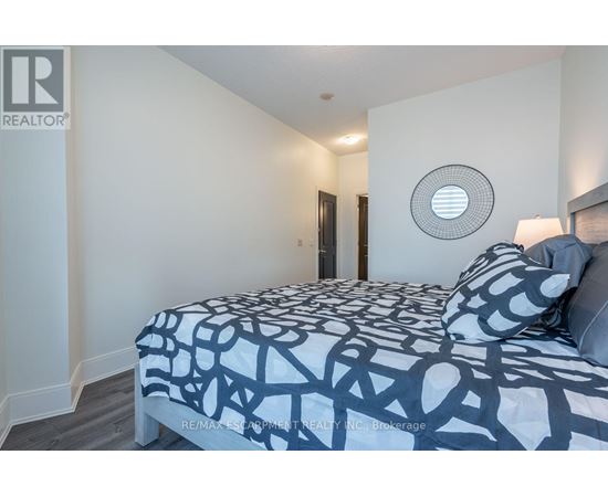 A bedroom with a bed covered in a black and white patterned comforter.