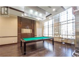 A pool table in a room with wooden floors and a large window.