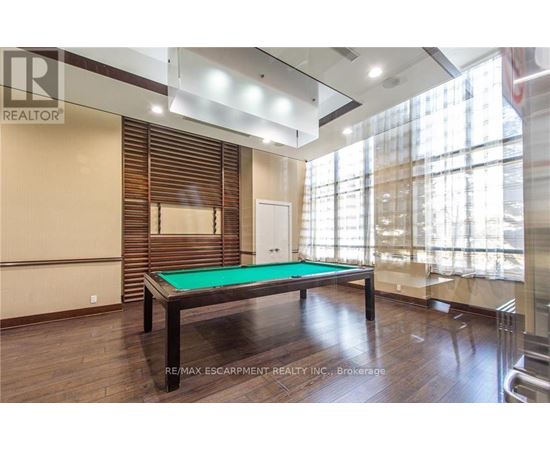 A pool table in a room with wooden floors and a large window.