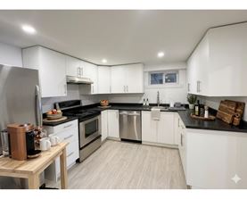 A modern kitchen with white cabinets and stainless steel appliances.