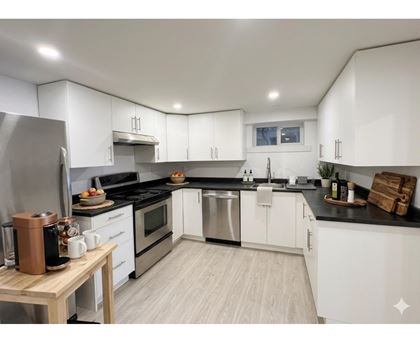 A modern kitchen with white cabinets and stainless steel appliances.