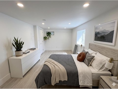 A bedroom with a large bed and a potted plant on a nightstand.