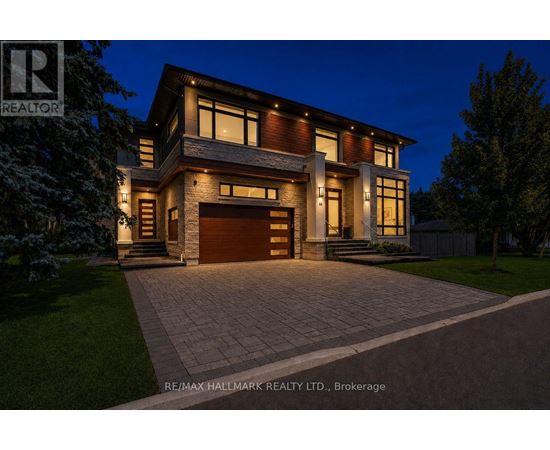 A modern house with a large driveway and garage is illuminated at night.