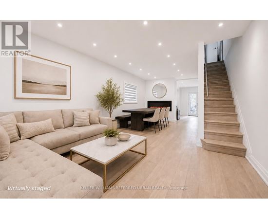 A living room with a couch, a coffee table, and a staircase.
