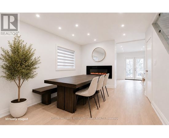 A modern dining room with a fireplace and a round mirror on the wall.
