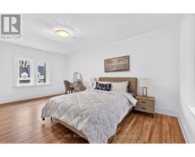 A bedroom with a large bed and a painting on the wall.