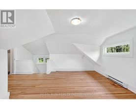 A spacious room with wooden flooring and white walls.