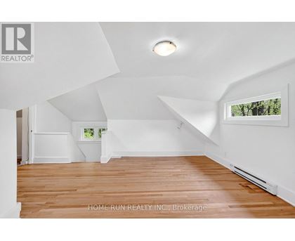 A spacious room with wooden flooring and white walls.