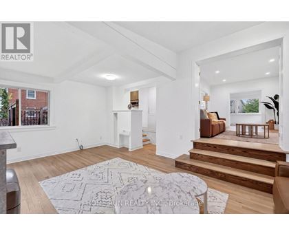 A spacious living room with a rug on the floor and a staircase leading to the upper floor.