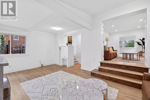 A spacious living room with a rug on the floor and a staircase leading to the upper floor.