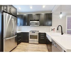 A modern kitchen with a stainless steel refrigerator and black cabinets.