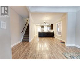 A spacious living room with hardwood floors and a staircase leading to the upper level.