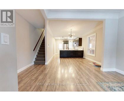 A spacious living room with hardwood floors and a staircase leading to the upper level.