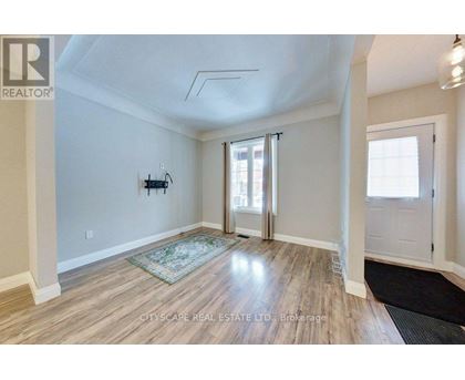 A spacious room with wooden flooring and a rug in the middle.