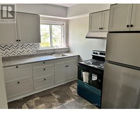A kitchen with a black fridge and white cabinets.