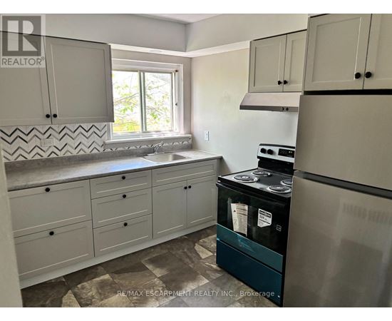 A kitchen with a black fridge and white cabinets.