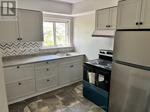A kitchen with a black fridge and white cabinets.