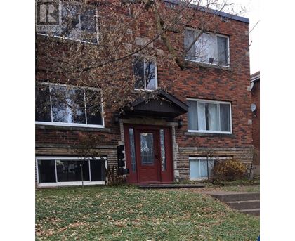 A red door is on the front of a brick building.