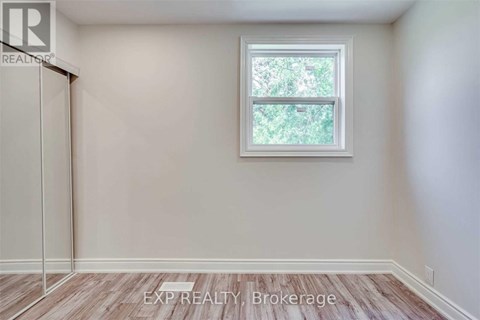 A room with a window and a wooden floor.