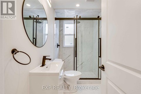 A bathroom with a toilet, sink, and mirror.