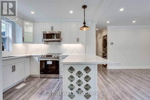 A kitchen with white cabinets and a wooden floor.
