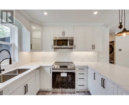 A modern kitchen with white cabinets and a stove top oven.