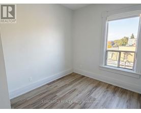 A room with a window showing a view of buildings and trees outside.