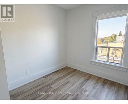 A room with a window showing a view of buildings and trees outside.