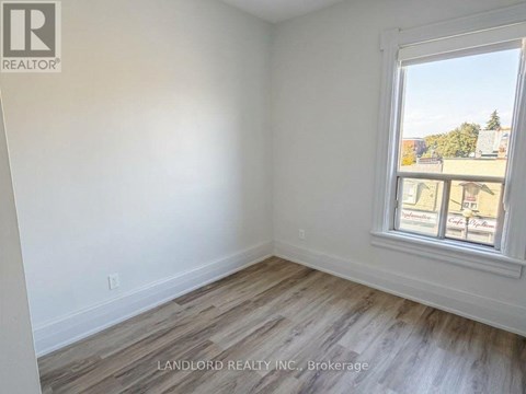 A room with a window showing a view of buildings and trees outside.