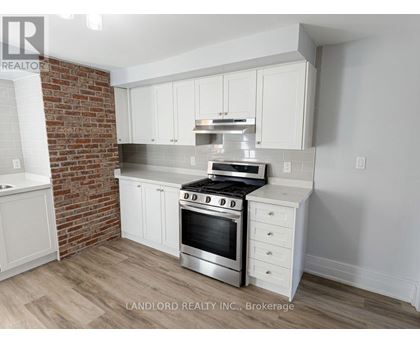 A kitchen with white cabinets and a brick wall.