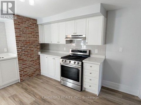 A kitchen with white cabinets and a brick wall.