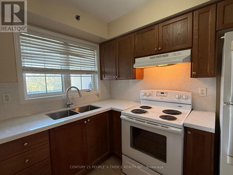 A kitchen with wooden cabinets and a white stove top oven.