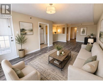 A living room with a beige couch, a coffee table, and a plant.