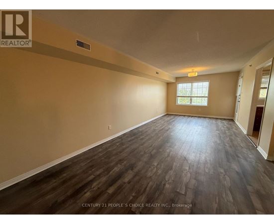 A spacious room with wooden flooring and a window.